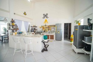 A modern kitchen with a central island, bar stools, a refrigerator, and a microwave.