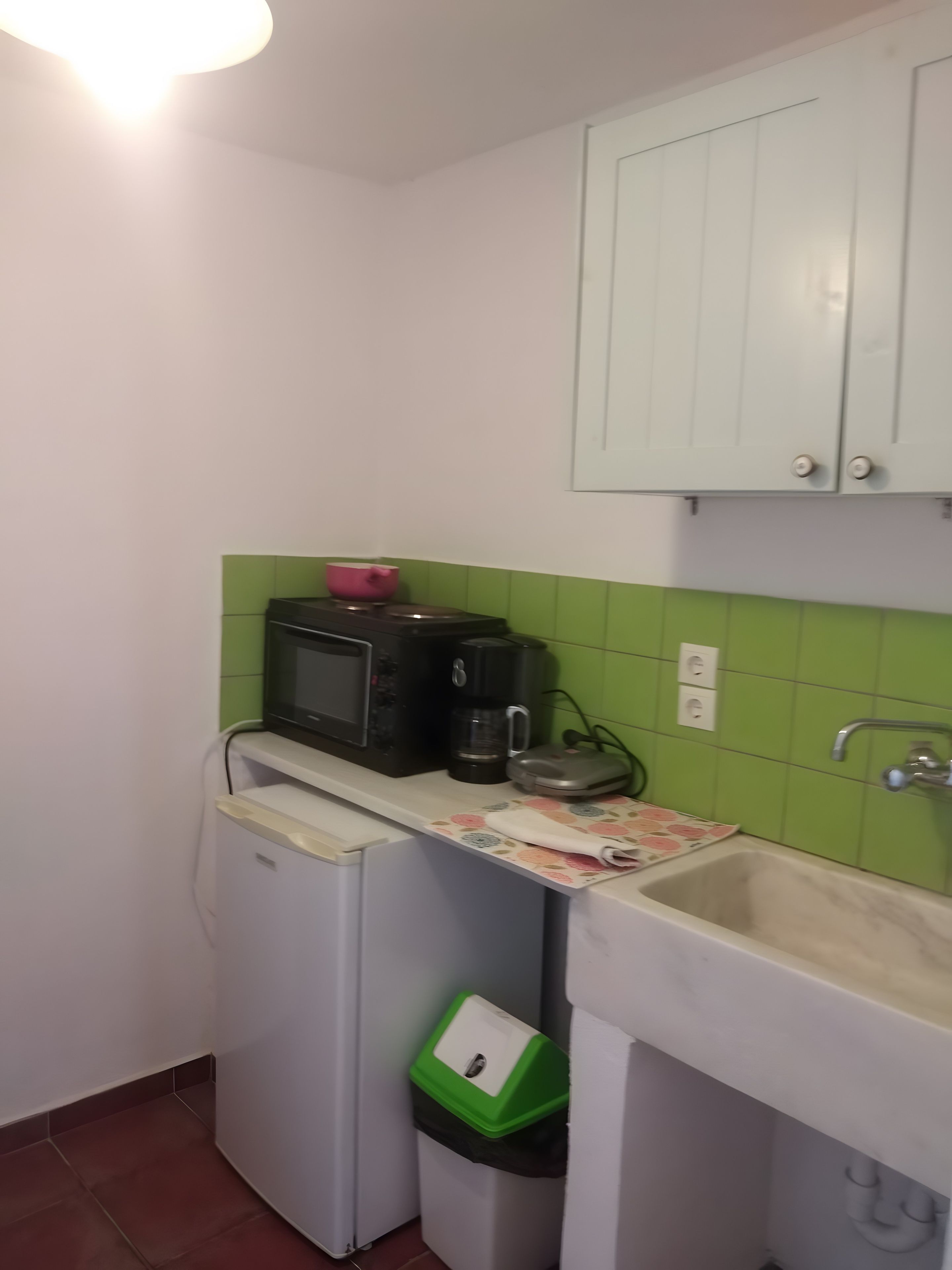Eine kleine Küche mit Mikrowelle, Kaffeemaschine und einem kleinen Mülleimer.