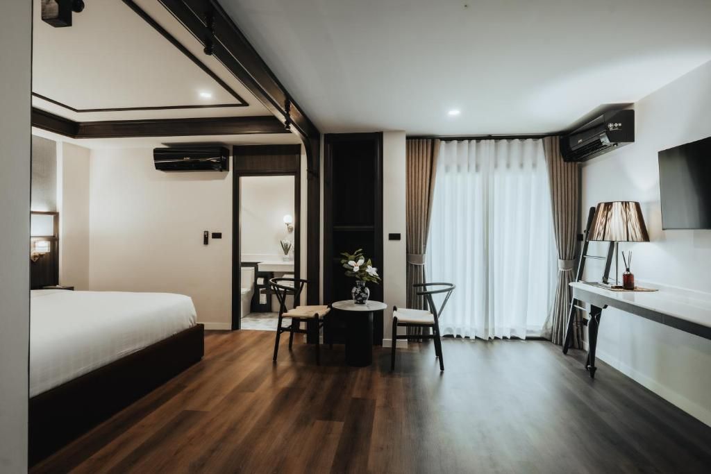 Una habitación de hotel con cama, una mesa de comedor con sillas, un televisor y un equipo de aire acondicionado.