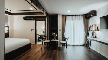 Una habitación de hotel con cama, una mesa de comedor con sillas, un televisor y un equipo de aire acondicionado.
