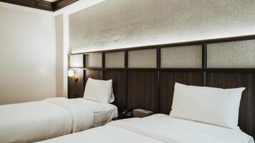Une chambre d’hôtel avec deux lits, une tête de lit en bois et une table de chevet avec une lampe.