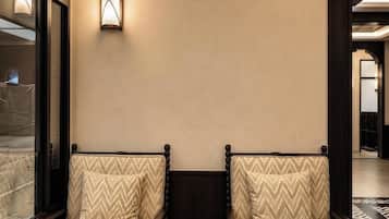 A modern hotel lobby with two upholstered chairs, a small round table, and a wall-mounted light fixture.