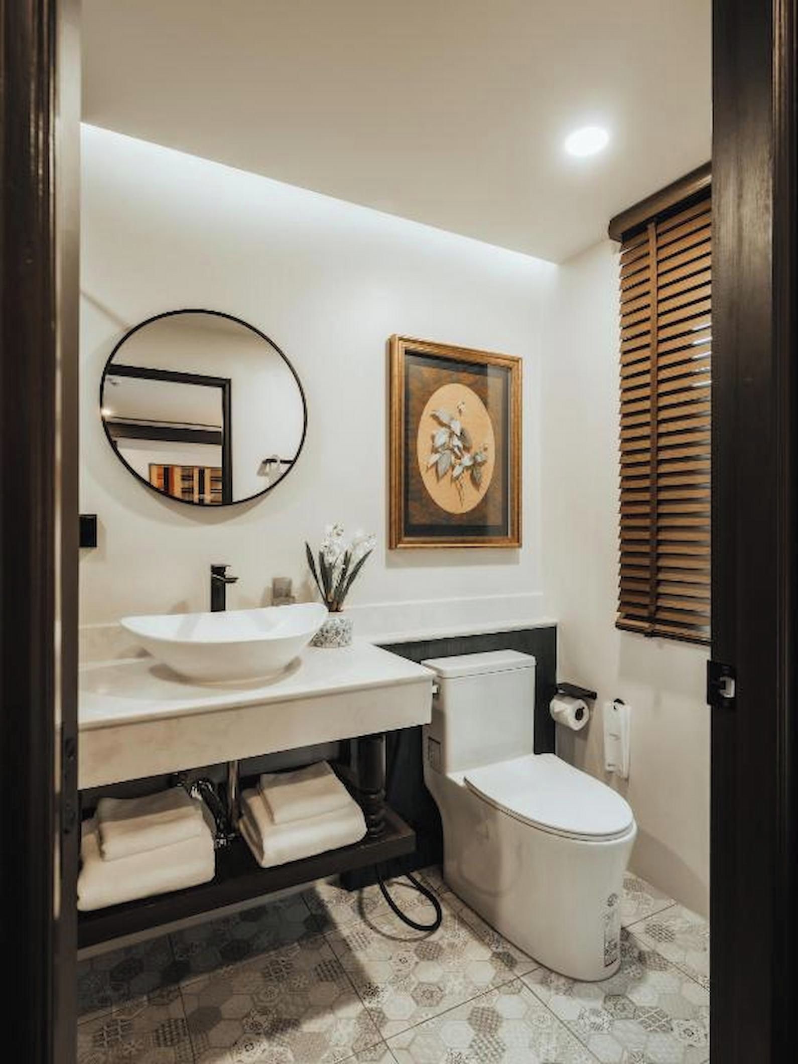 Un baño con un lavamanos blanco, un inodoro, un espejo y un cuadro en la pared.