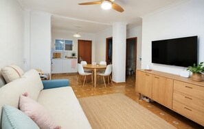 A modern living room with a sofa, TV, and a dining area with chairs and a table. - 2 bedroom stunning apartment in San Javier (San Javier)