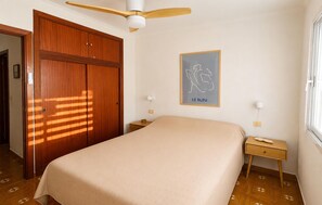A bedroom with a bed, a wooden wardrobe, a ceiling fan, a bedside table with a lamp, and a framed artwork on the wall. - 2 bedroom stunning apartment in San Javier (San Javier)