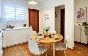A dining area with a round table, chairs, and a kitchen in the background. - 2 bedroom stunning apartment in San Javier (San Javier)