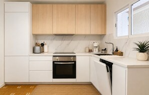 A modern kitchen with white cabinetry, a built-in oven, a dishwasher, and a window above the sink. - 2 bedroom stunning apartment in San Javier (San Javier)