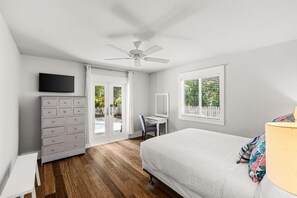 Ein Schlafzimmer mit Bett, Schreibtisch, Fernseher, Kleiderschrank und Deckenventilator.