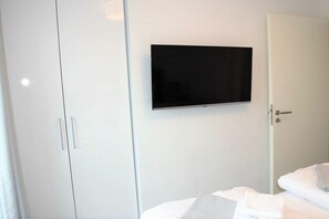 A hotel room with a bed, a wardrobe, and a television mounted on the wall. - Holiday apartment with 1 bedroom (Wangerland)