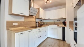 A modern kitchen with white cabinetry, a wooden countertop, and a built-in oven. - 2-CEVAA013 (Praz-sur-Arly)