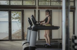 Una persona usando una cinta de correr en una habitación con ventanas amplias con vistas a la playa.