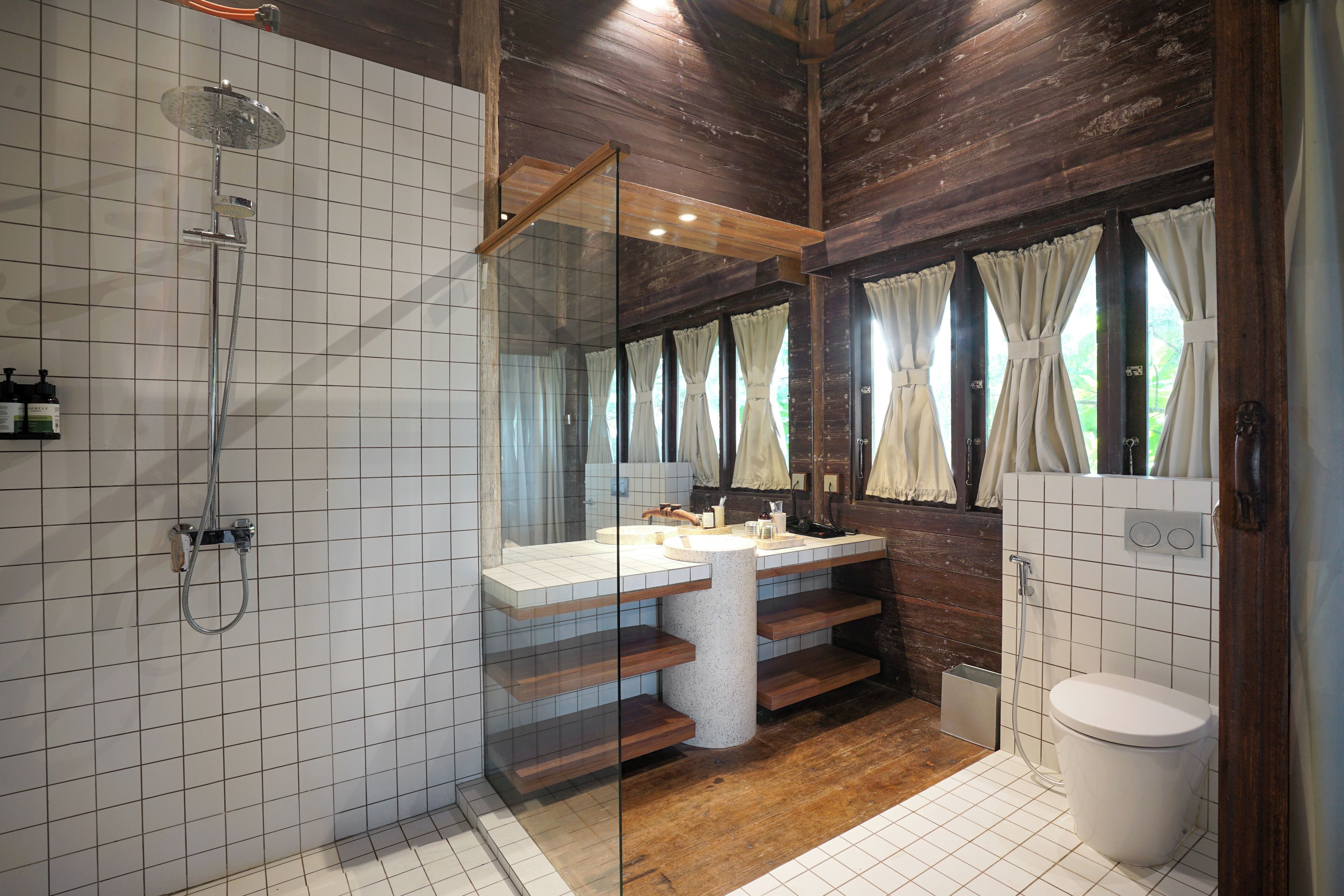 Une salle de bain avec une douche à parois de verre, un meuble-lavabo en bois et des toilettes.