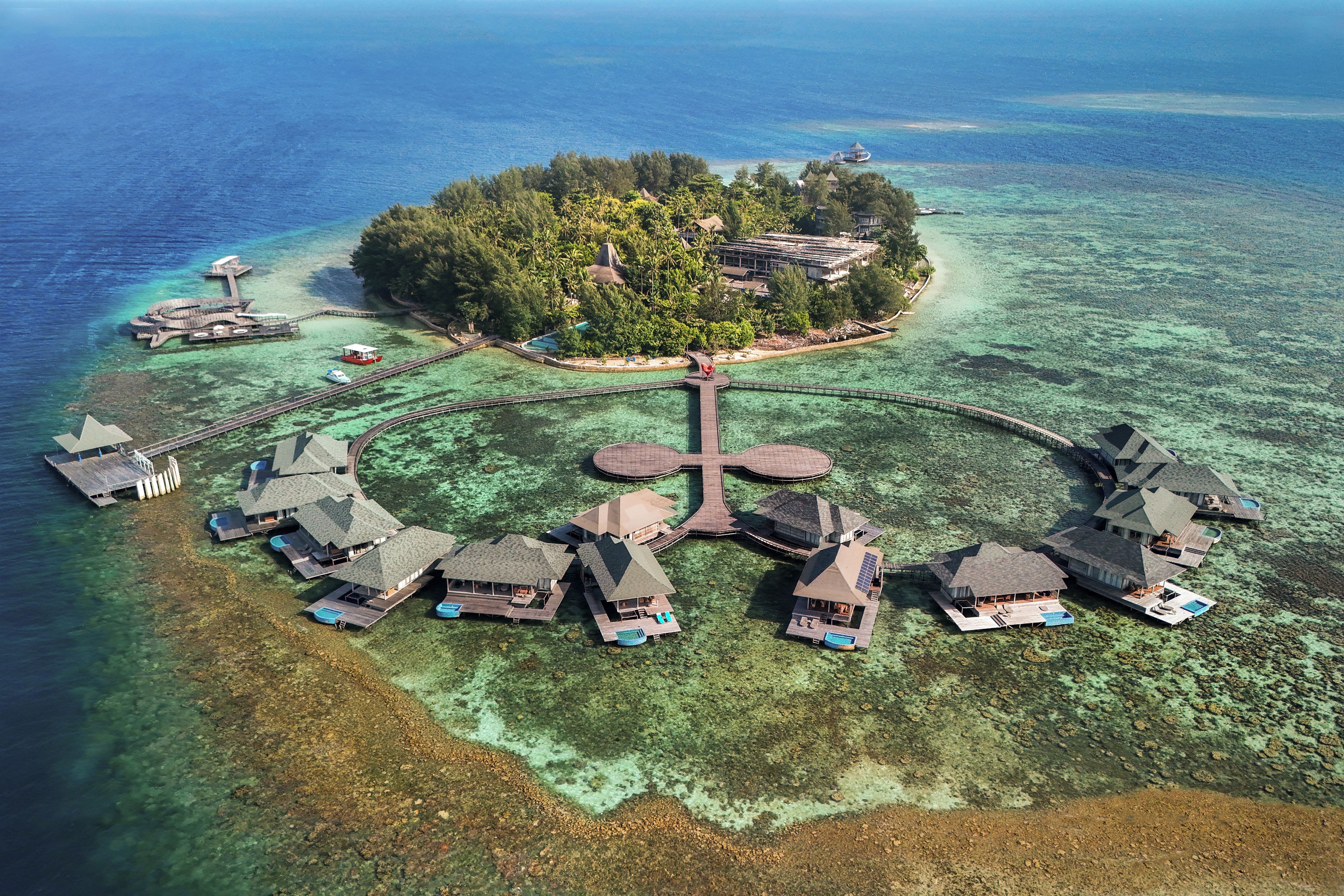 Vista aérea de un resort tropical con varias cabañas sobre el agua conectadas por pasarelas.
