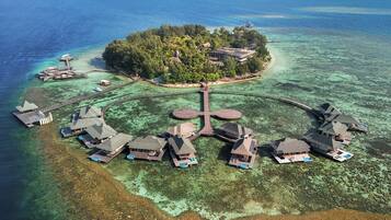 Vista aérea de un resort tropical con varias cabañas sobre el agua conectadas por pasarelas.
