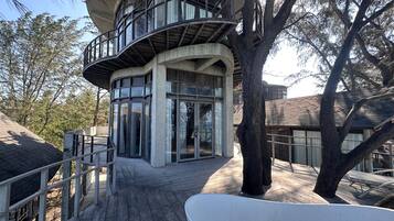 A modern building with a curved balcony, large windows, and a wooden deck.