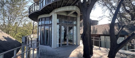 A modern building with a curved balcony, large windows, and a wooden deck.