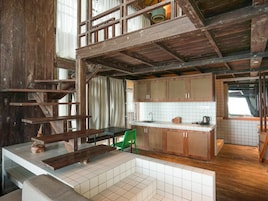 Una cocina rústica con vigas de madera, salpicadero de azulejos y una silla verde.