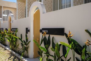 A row of hotel rooms with individual doorways, each marked with a nameplate. - Villa Naya by Betterplace (Pecatu)