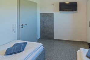 Une chambre d’hôtel équipée d’un lit, d’un téléviseur fixé au mur et d’un espace douche.