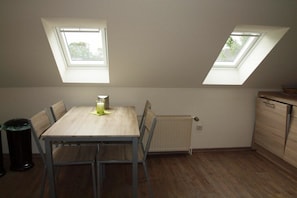 Ein Zimmer mit einem Holztisch, zwei Stühlen, einer Heizung und einem Fenster.