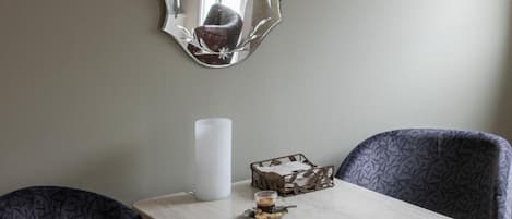 A dining area with a table, chairs, a candle, and a decorative mirror.