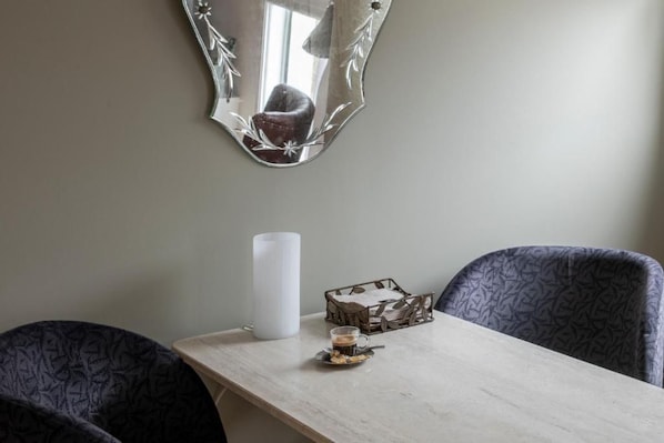 A dining area with a table, chairs, a candle, and a decorative mirror.