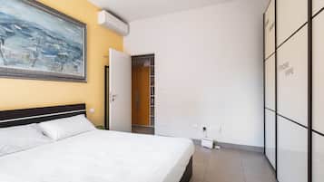 Quarto de hotel com cama, guarda-roupa, um quadro na parede e ar condicionado.