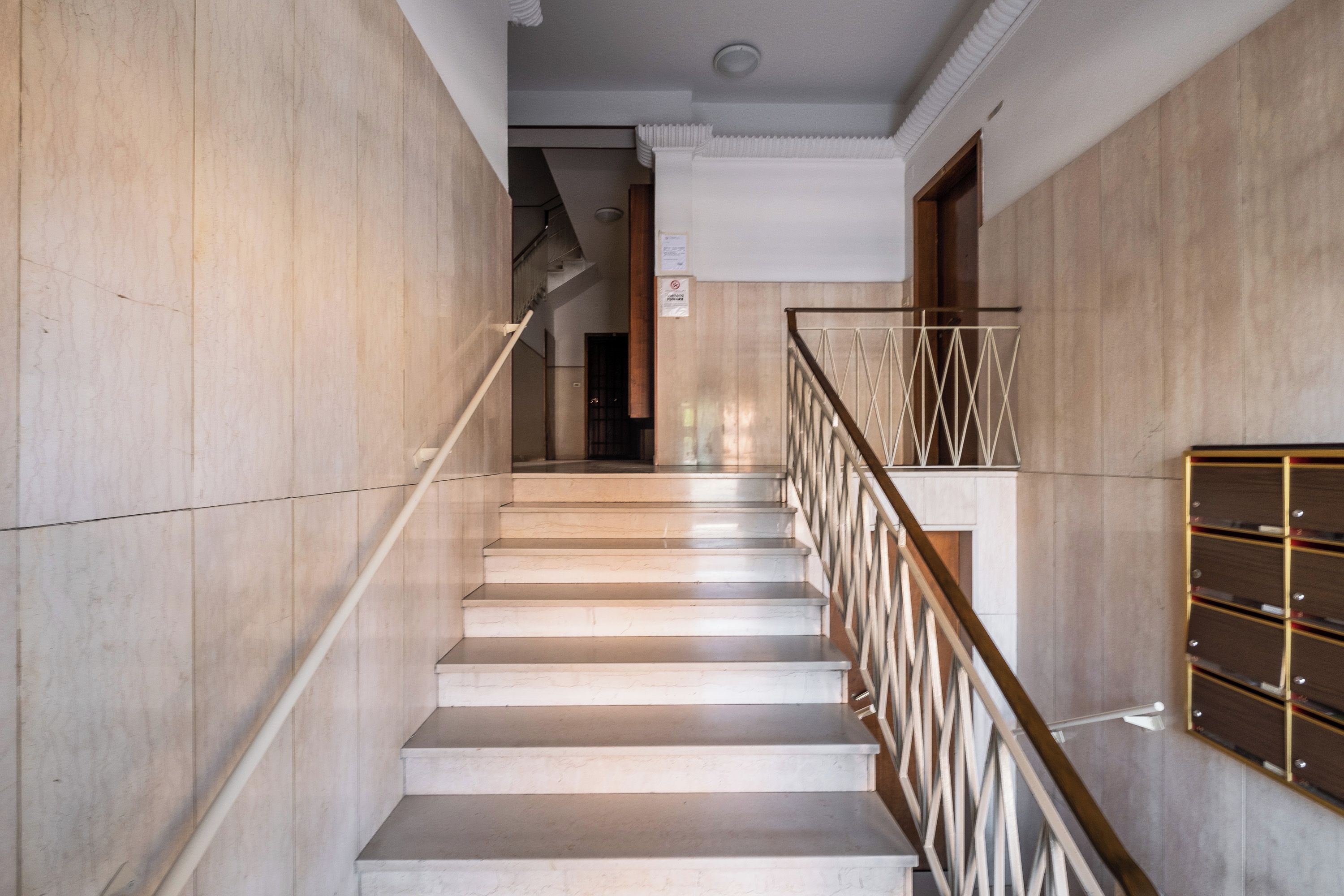 A staircase with a metal railing and a wall-mounted mailbox.