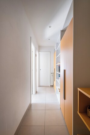 A narrow hallway with a door at the end, a radiator, and a shelf with items on it. - Bergonzoni Modern Apartment by Wonderful Italy (Bologna)