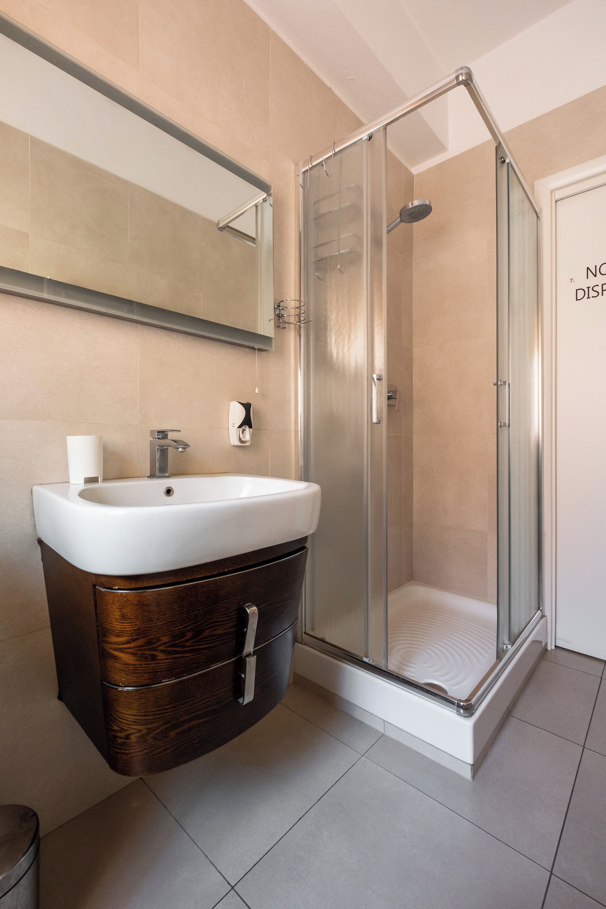A bathroom with a sink, mirror, and shower.