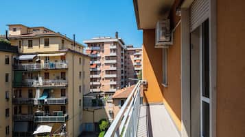 Edifício residencial com várias sacadas, céu claro e vista para edifícios vizinhos.
