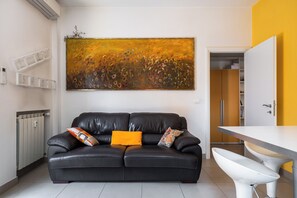 A modern living space with a black leather sofa, a white table, and a large abstract painting on the wall. - Bergonzoni Modern Apartment by Wonderful Italy (Bologna)