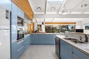 A modern kitchen with blue cabinets, a built-in oven, and a large island with a sink. - Ocean View House Fairhaven (Fairhaven)