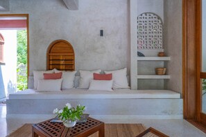 A room with a built-in bench, a small table with a plant, and a decorative wall panel. - Waridi North | Breeze – 2BR Upper Floor (Diani Beach)