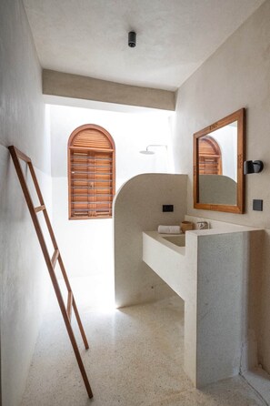 A bathroom with a wooden ladder, a sink, a mirror, and a window with wooden shutters. - Waridi North | Breeze – 2BR Upper Floor (Diani Beach)