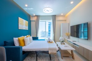 Ein modernes Hotelzimmer mit Bett, Schreibtisch, Fernseher und Blick auf die Stadt.