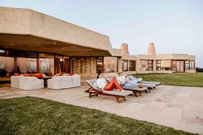 A modern outdoor lounge area with wicker furniture and a stone patio.