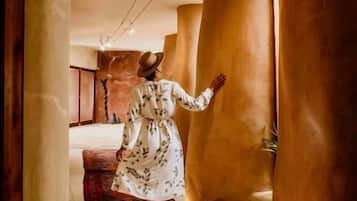 A corridor with large cylindrical columns, a person in a dress, and a carpeted floor.