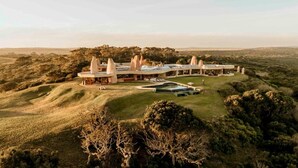 A large, modern building with multiple structures, surrounded by a lush landscape. - Sandcastle (Wesley)