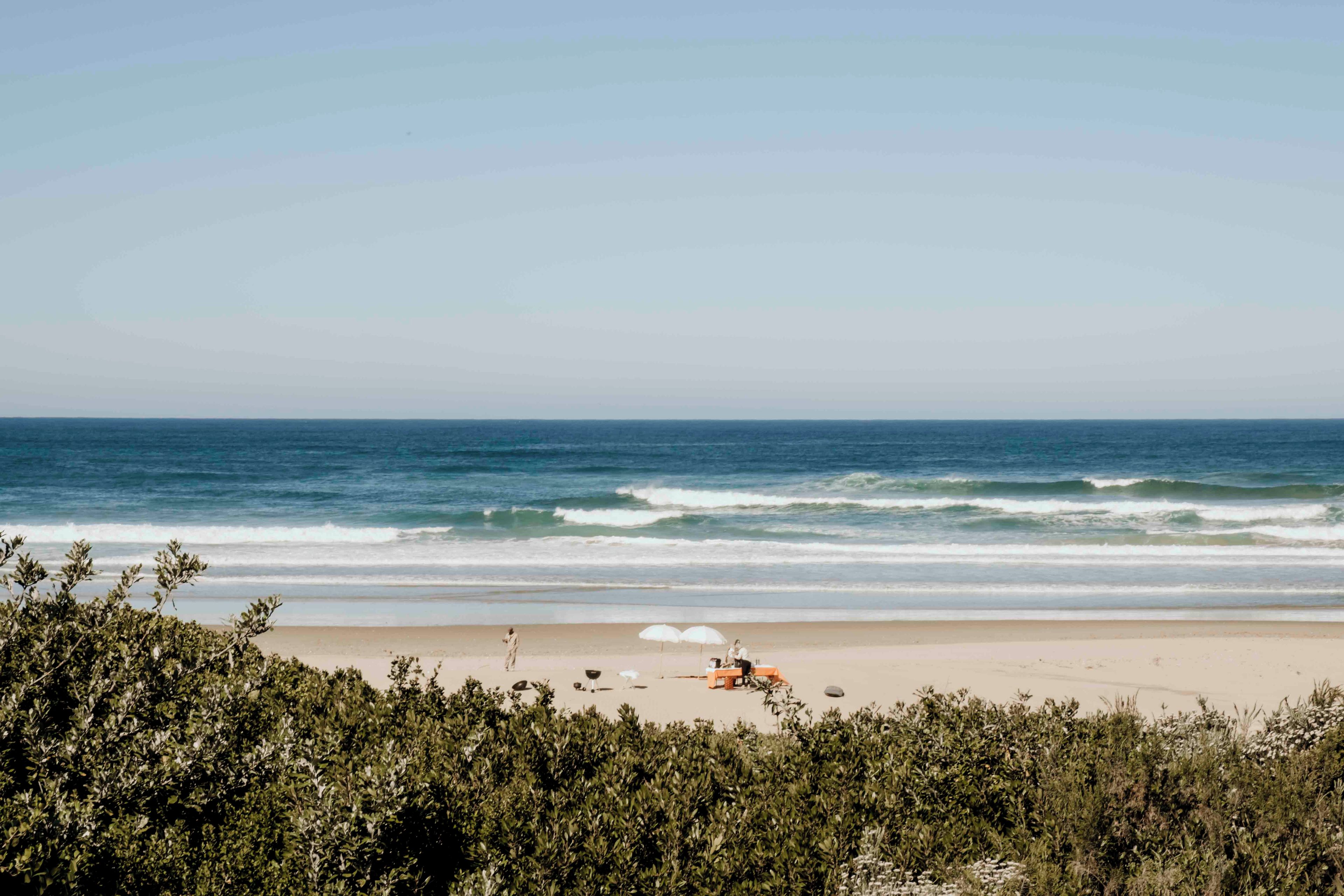 A beach with a sandy shore, waves, and a clear sky.