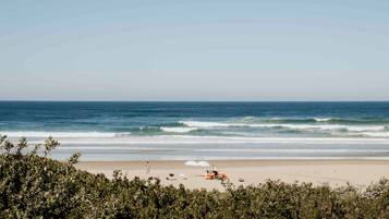 A beach with a sandy shore, waves, and a clear sky.