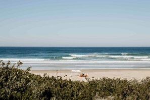 A beach with a sandy shore, waves, and a clear sky.