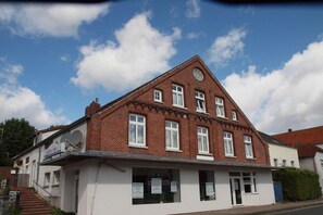 A two-story building with a symmetrical facade, multiple windows, and a satellite dish on the side. - Holiday apartment with 2 bedrooms (Carolinensiel)