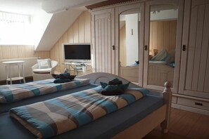 A bedroom with two beds, a television, a chair, and a wardrobe. - Holiday apartment with 2 bedrooms (Carolinensiel)