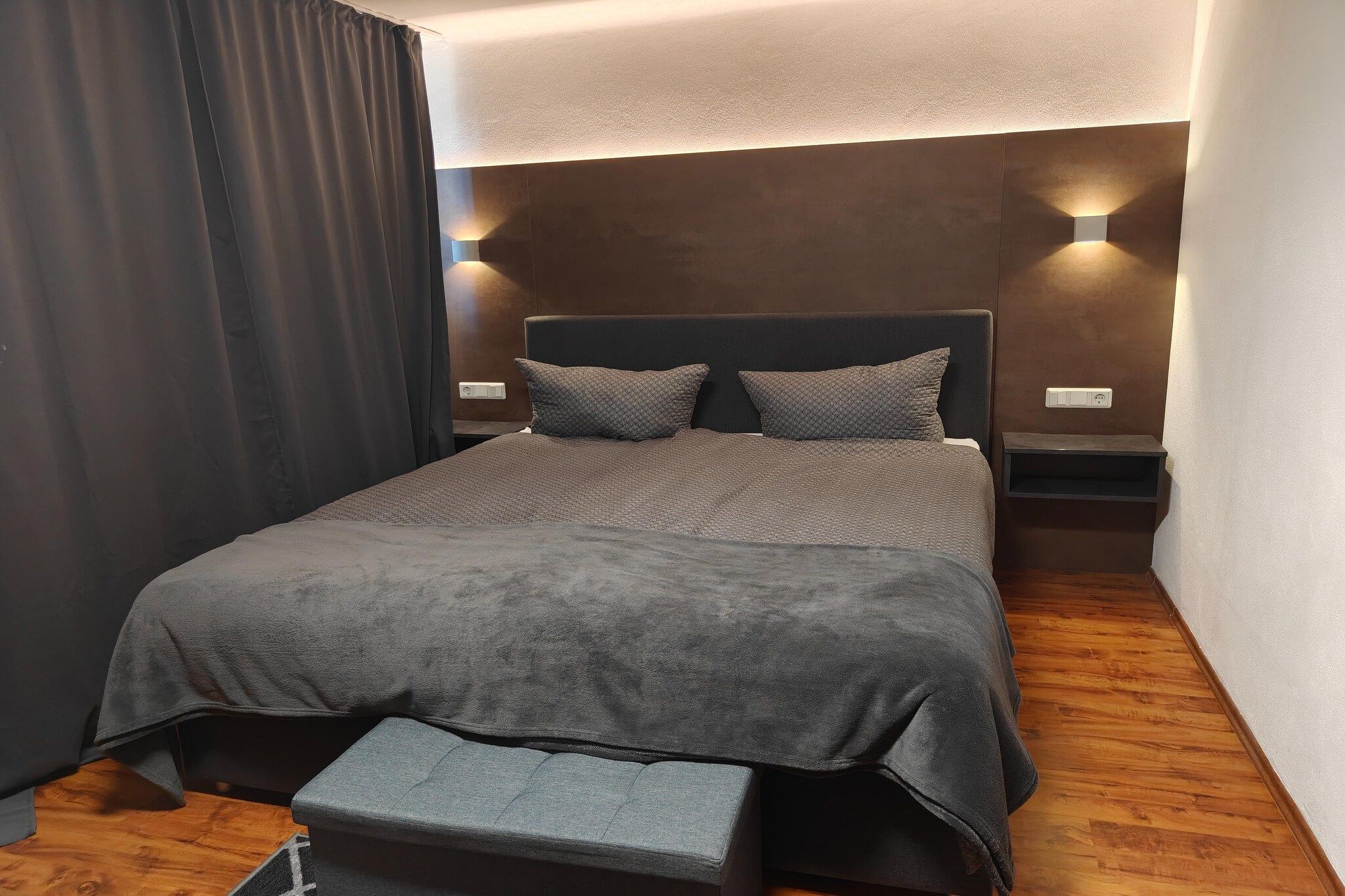 Ein Schlafzimmer mit einem Bett, einer Bank und zwei Wandleuchten.