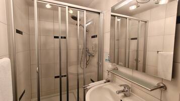 Un bany modern amb dutxa de vidre, un lavabo amb mirall i una barra de tovalloles.