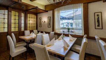 Ein Restaurant mit Holzvertäfelung, weißen Stühlen und einem großen Fenster mit Blick auf die Straße.