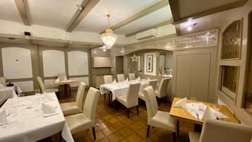 Comedor con varias mesas dispuestas para comensales, sillas y una araña.