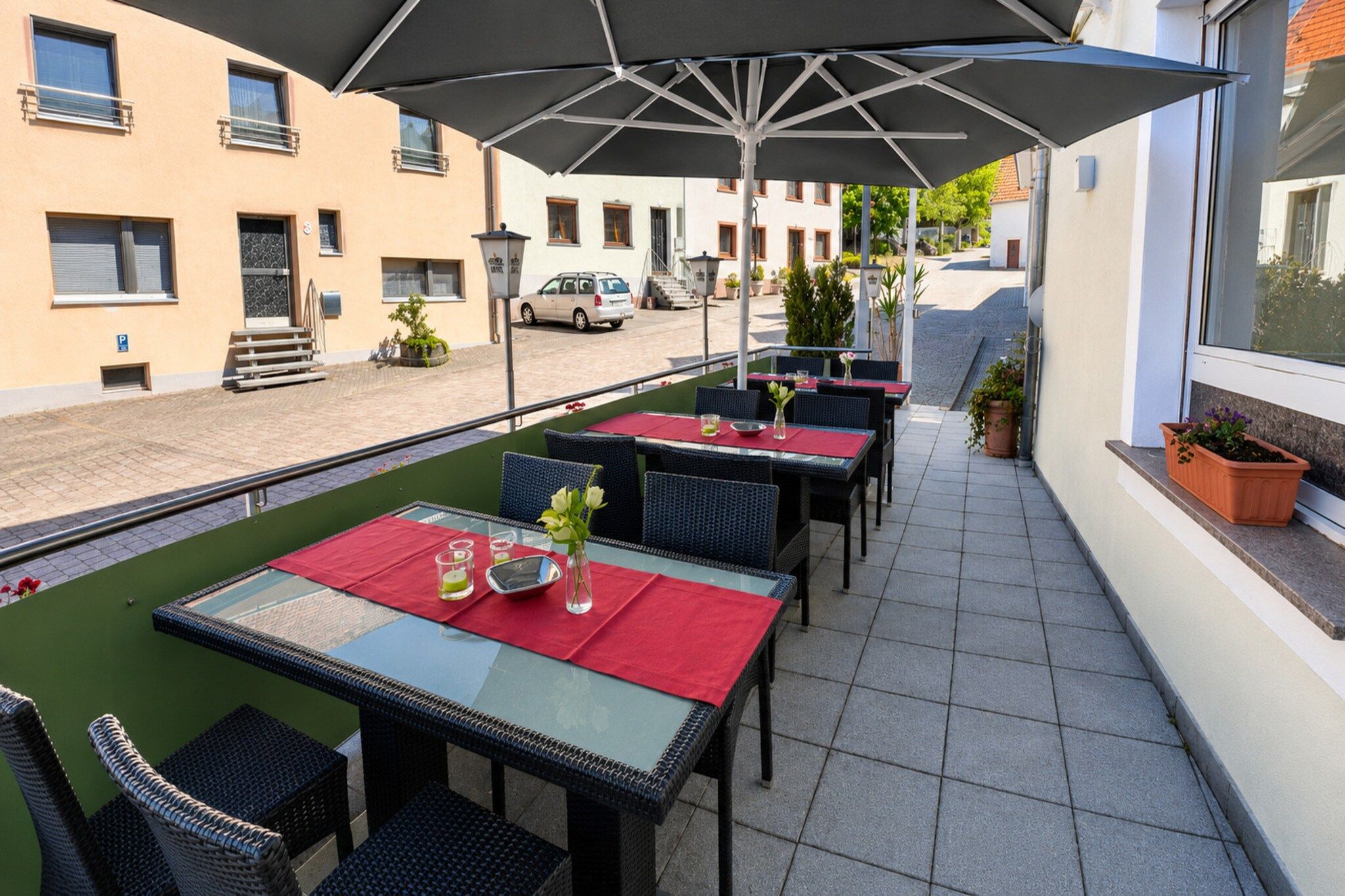 Eine Terrasses mit Tischen und Stühlen, einem überdachten Bereich und Blick auf die Straße.