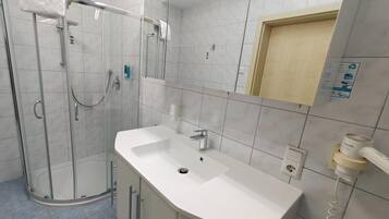 Ein modernes Badezimmer mit einer gläsernen Dusche, einem weißen Waschbecken und einem Spiegel.